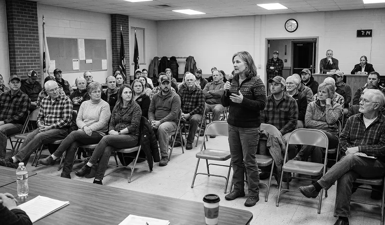 Person standing and speaking in front of a community gathering