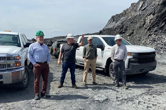 Construction people standing in front of some trucks at a site